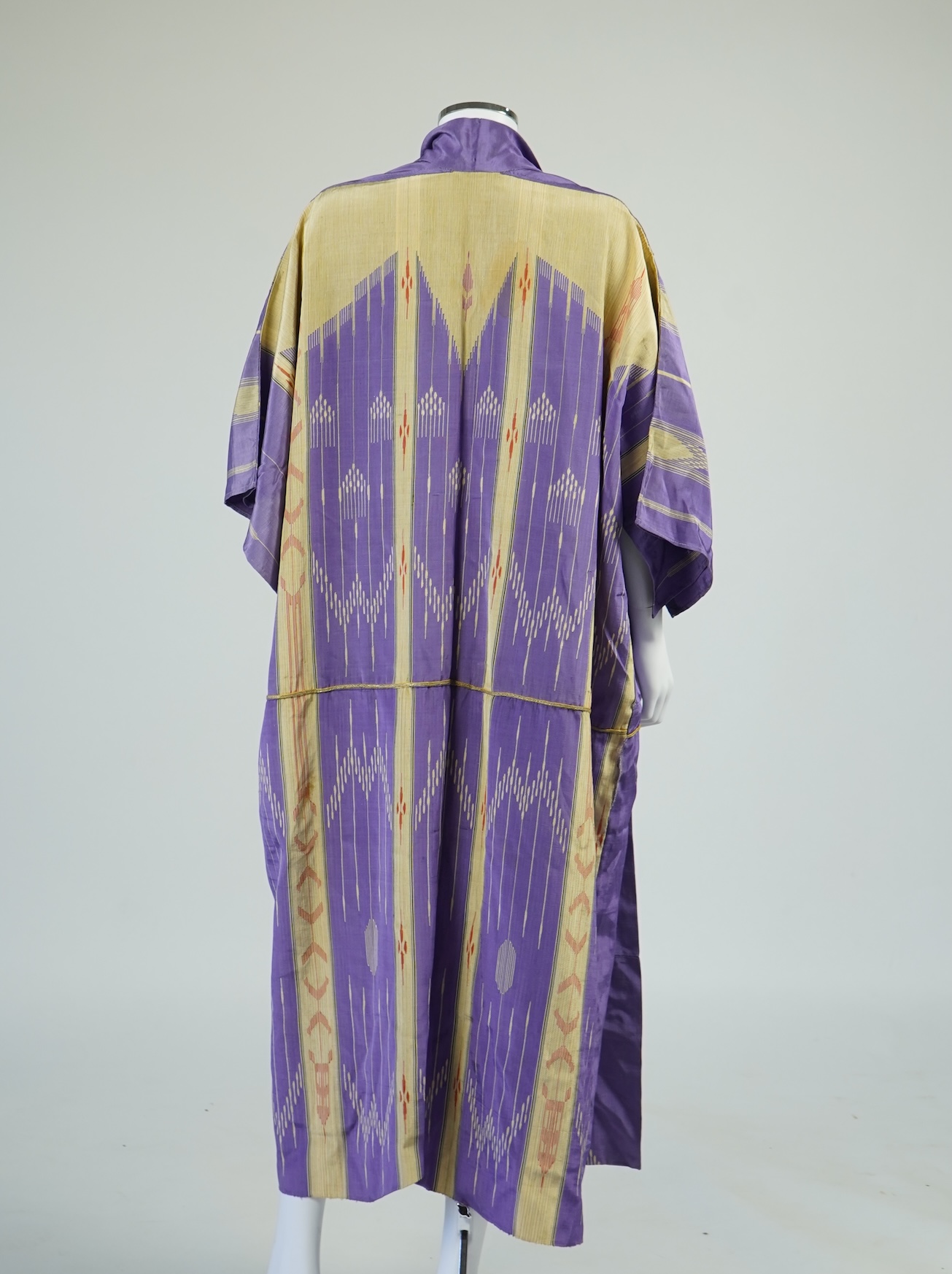 An early 20th century Syrian hand woven silk coat. Woven with stripes and geometric shapes in purple and yellow and red., 130 cm long. Condition - good, colours and fabric strong.